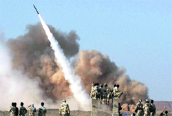 Iranian Revolutionary Guards personnel watch the launch of a Zelzal missile outside the city of Qom on Tuesday