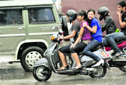 Three girls on a scooter enjoy themselves in the rain in Dehradun on Wednesday
