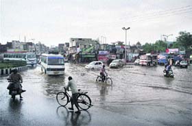 Commuters wade through the waterlogged Dogra Chowk in Jammu on Wednesday
