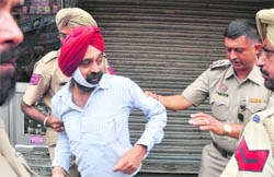 A shopkeeper being taken away by policemen following a demolition drive in the Field Ganj area on Wednesday. 
