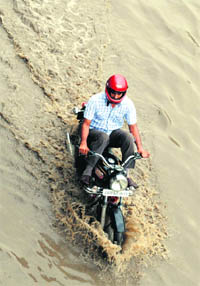A biker crosses a waterlogged road after heavy rain in Patiala on Wednesday. 