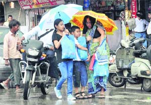 The members of a family huddle during heavy rain that lashed Dehradun on Thursday.