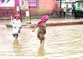 Women wade through rainwater at Fatehabad on Thursday