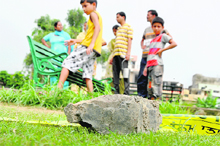 Curious bystanders, including children, look at a stone used for hitting to death Rajiv (29) and Sandeep (31) at a park in Subash Nagar in Ludhiana. 