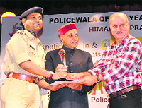Bollywood actor Anupam Kher, along with Chief Minister PK Dhumal, presents an award to a policeman in Shimla on Friday