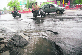 A damaged road near the Civil Secretariat in Jammu gives a tough time to motorists. The recent spell of rain has exposed the use of poor quality material in the recarpeting of roads in the city.
