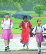 Schoolchildren and their mother caught the rain in New Delhi