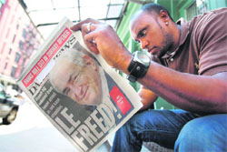 A man reads a paper with Dominique Strauss-Kahn on the front cover outside the New York apartment where the former IMF chief is staying
