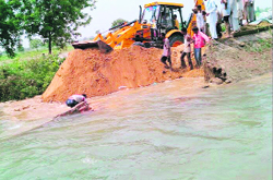 Workers of the Irrigation Department try to plug a breach in the Sukhchain distributary near Hanspur in Fatehabad on Monday. 