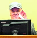 Former Bosnian Serb military chief Ratko Mladic waves in the courtroom during his appearance at the UNs Yugoslav war crimes tribunal in The Hague 