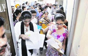 Students with their parents wait to get their forms checked on the first day of BCom admissions in Ludhiana on Tuesday. 
