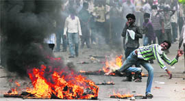 A pro-Telangana supporter throws a stone towards police personnel during the bandh in Hyderabad on Tuesday.