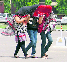 Three girls share a ‘dupatta’ to keep the sizzling heat at bay in Ludhiana on Wednesday