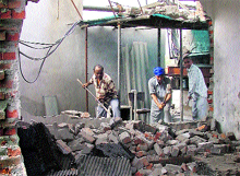 Workers of the Municipal Corporation demolish a structure on the third floor of Calibre Plaza in Ludhiana on Wednesday