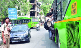 Schoolchildren hang from the door of a low-floor bus that has an automatic door lock system, but is of no use when the vehicle gets overcrowded.