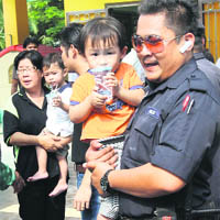 A policeman carries a kindergarten student after the end of a hostage drama in Muar, Malaysia