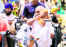 A physically-challenged man wipes his sweat as the function was organised in an open ground on a hot day in Ludhiana