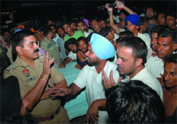 A police official tries to pacify agitated Bhokhra villagers near the Nehianwala police station in Bathinda late on Sunday evening