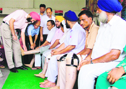 Members of the Bharat Vikas Parishad, an NGO, distribute artificial limbs among the needy in Ludhiana