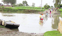 Villagers near the Radcliffe Line wade through knee-deep water. The temporary bridge over the Sutlej creek has been damaged