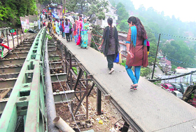  People walk on a temporary bridge, which is without a railing, at the Lakkar Bazar in Shimla on Tuesday