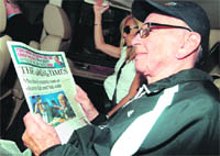 News Corporation Chief Rupert Murdoch reads a copy of the London Times newspaper as he arrives at his London home on Tuesday.