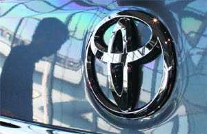 A visitor is reflected on a Toyota vehicle at the company's showroom in Tokyo on Wednesday. Toyota Motor Corp said on Wednesday it would buy out the remainder of Toyota Auto Body and Kanto Auto Works it does not already own through share swaps on January 1 next year