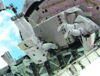 Astronaut Ron Garan (left), who is attached to the International Space Station's Canadarm2, holds the pump module as he is assisted by fellow spacewalker Mike Fossum as they secure the module in Atlantis' payload bay for its return to the earth. 