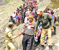 Police personnel help devotees cross a glacier on the Baltal route