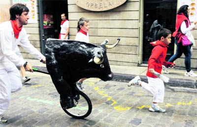 Children sprint in front of a toy bull during the San Fermin festival's bull run for children in Pamplona, Spain, on Wednesday. Six toy bulls driven by runners take part in the children bull run, which imitates the morning running of the bulls for adults, but for a much shorter distance.
