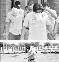 Members of the gang being taken to the district courts (top); and a policeman walks past the recovered vehicles at Mohali on Thursday