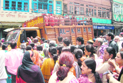 Consumers gather around a truck carrying LPG cylinders in Mussoorie on Thursday