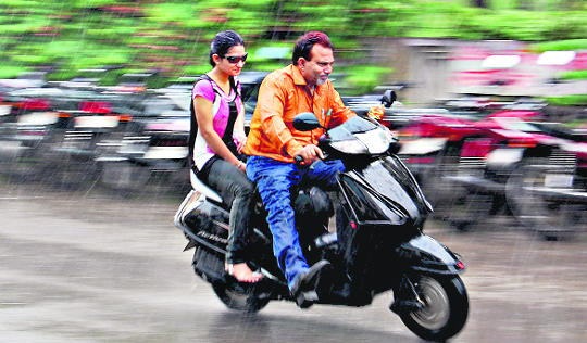 A scooterist along with his daughter rushes to his home after being caught in the rain in Jalandhar.