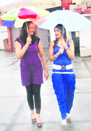 Two women holding umbrellas enjoy a walk in the rain in Jalandhar.