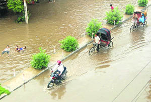 Commuters wade through a flooded street after a downpour in Jalandhar 