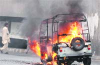 A man walks past an ablaze three-wheeler in Karachi. 