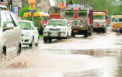 Commuters wade their way through a waterlogged stretch on the Zirakpur-Patiala highway on Friday. 