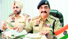Police officials show the recovered amount in Ludhiana on Friday.