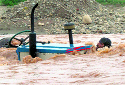 A man holds his tractor as he struggles to come out of the flooded Tawi in Jammu on Saturday