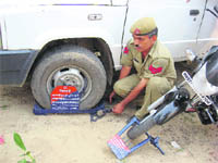 A traffic policeman fixes a special lock on vehicles parked unauthorisedly in Kurukshetra.