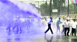 The police sprays coloured water from a cannon on protesting government employees, near the Civil Secretariat, in Srinagar on Monday.
