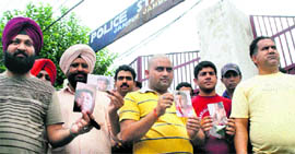Shopkeepers hold photos of a cheat who duped them in Jammu on Monday.