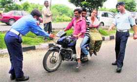 A traffic policeman tries to stop a motorcyclist with two pillion riders at Brigadier Rajinder Singh Chowk in Jammu on Monday.
