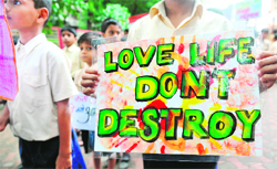 Schoolchildren hold placards as they take out a silent march in memory of those killed in the serial blasts on July 13, in Mumbai on Wednesday.