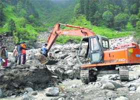 Rohtang tunnel site workers use a JCB machine to cross over to Fingri Nullah, about 21 km from Manali, on the Solang-Dhundi-Rohtang tunnel road on Thursday