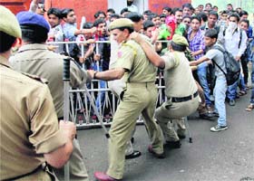 Policemen try to stop students protesting against the delay in the start of Jammu Central University in Jammu on Thursday