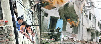 Residents look on as MC officials (right) carry out a demolition drive near the Khalsa College for Women in Ludhiana on Thursday. 