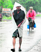 People use polythene sheets to protect themselves from rain in Amritsar.