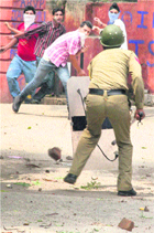 Students pelt stones at a policeman during a protest over the delay in the start of the Central University of Jammu, on the Canal Road in Jammu on Friday