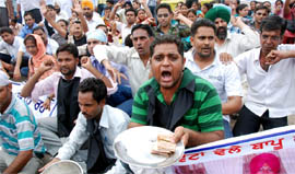 Rural health pharmacists hold begging bowls while staging a protest inside the main bus stand in Bathinda on Saturday.